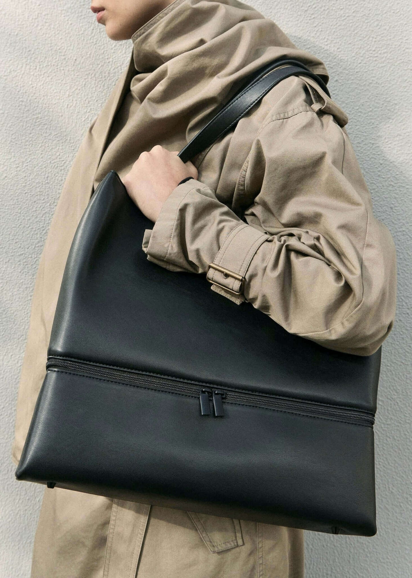 close up of model holding a black vegan leather lunch bag outside
